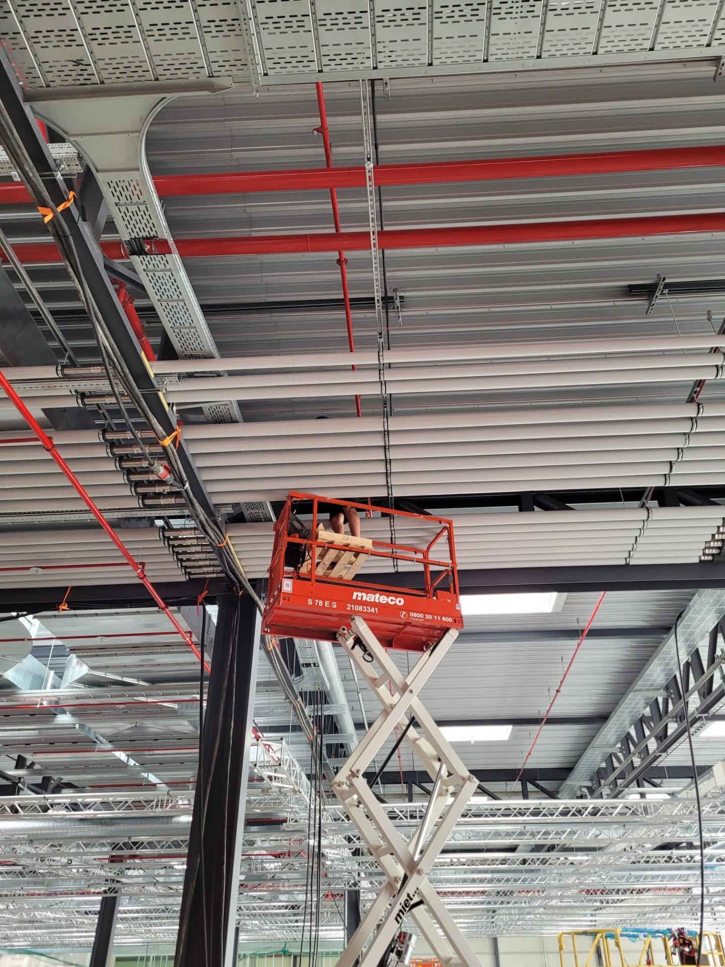 Overhead HVAC, sprinkler and cable-tray installation in a logistics hall.